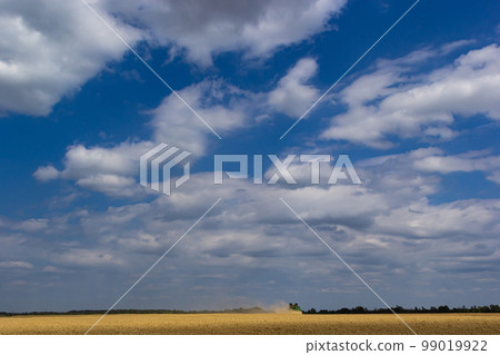 Photo of combine harvester that is harvesting wheat with dust straw in the air Photo of combine harvester that is harvesting wheat with dust straw in the air 99019922