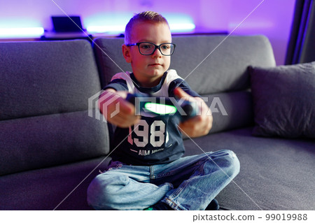 Boy Danya in glasses plays on a game console. Boy Danya in glasses plays on a game console. 99019988