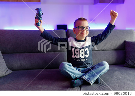 Boy Danya in glasses plays on a game console. 99020013