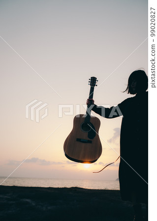 Photo of a young woman playing guitar 99020827