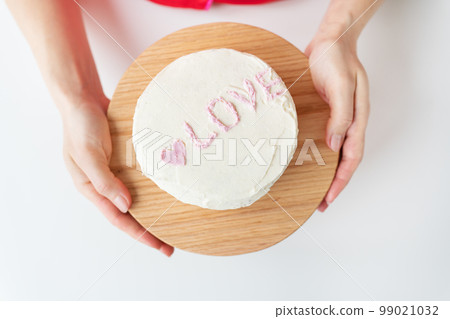 The girl is holding a Bento cake with the inscription Love and hearts. A small Korean cake for one person. A cute dessert gift for a loved one for any holiday. Valentine's Day. The girl is holding a Bento cake with the inscription Love and hearts. A small Korean cake for one person. A cute dessert gift for a loved one for any holiday. Valentine's Day. 99021032