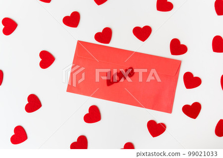 A love letter, the inscription of love on a red paper envelope on the background of small red hearts. The concept of St. Valentine's Day. A love letter, the inscription of love on a red paper envelope on the background of small red hearts. The concept of St. Valentine's Day. 99021033