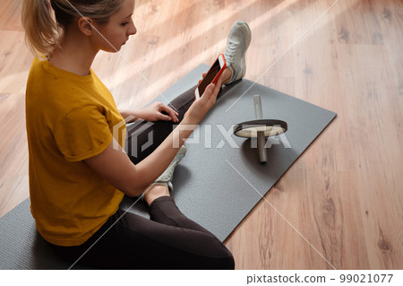 Young pretty woman using smartphone for yoga or workout online 99021077
