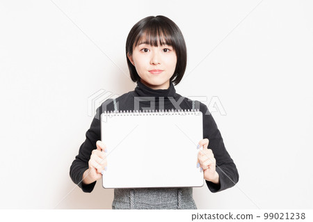 Young woman showing a small sketchbook Young woman showing a small sketchbook 99021238