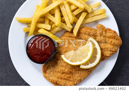 Wiener schnitzel with fried potatoes on black background 99021402