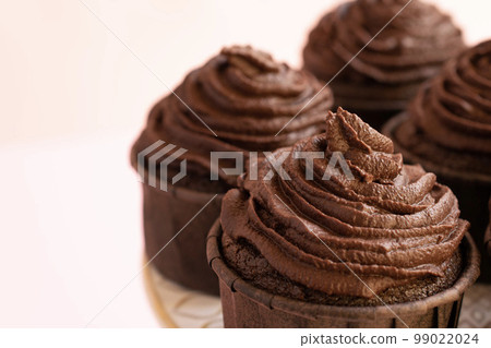 Close up of chocolate cupcake on pink background 99022024
