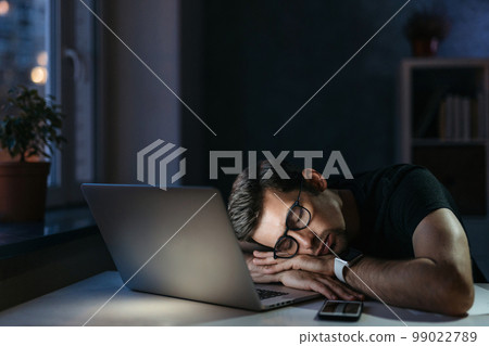 Overworked man sleeping on laptop at night Overworked man sleeping on laptop at night 99022789