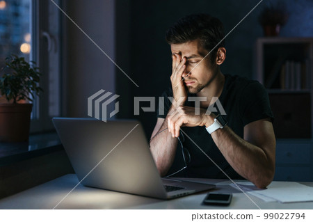 Young overworked man with laptop at night Young overworked man with laptop at night 99022794