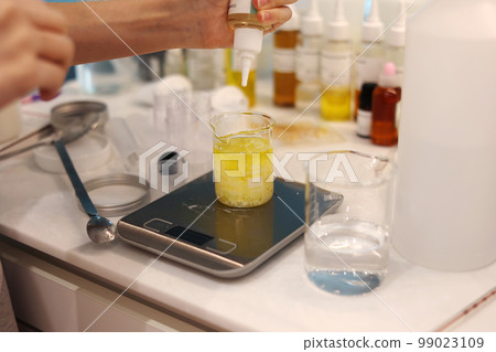Mixing of solutions in a beaker placed on a scale in a laboratory with bottles of various solutions Mixing of solutions in a beaker placed on a scale in a laboratory with bottles of various solutions 99023109