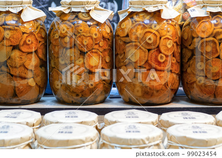 Canned pickled mushrooms in glass jars on shelf in market in Russia. 99023454