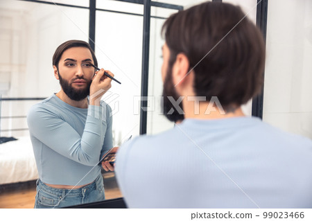 Guy looking at the mirror during the eye makeup application 99023466