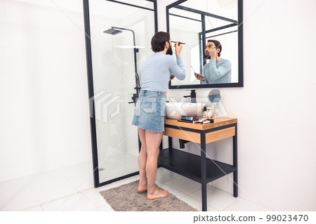 Guy applying the eyeshadows to his upper eyelid 99023470