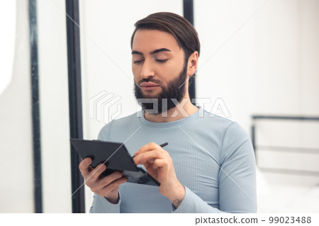 Young man using a brush for blending eye shadows 99023488