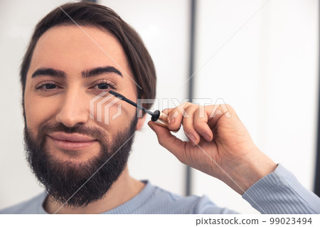 Pleased transgender person using the eye cosmetics 99023494