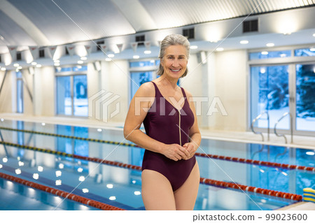 Elderly smiling woman standing at the swimming pool Elderly smiling woman standing at the swimming pool 99023600