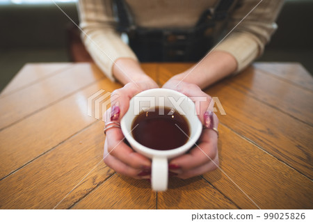 Woman's hand holding a coffee cup Woman's hand holding a coffee cup 99025826