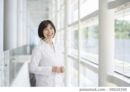 A smiling young woman in a white coat looking at the camera portrait 99026390