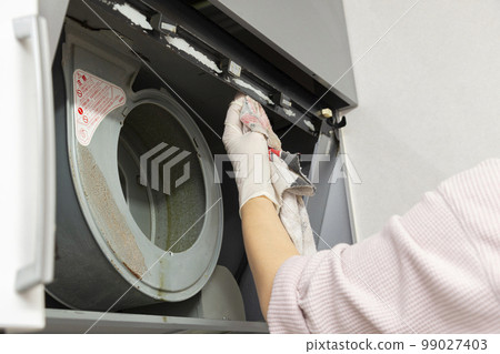 Woman cleaning the ventilation fan in the kitchen 99027403