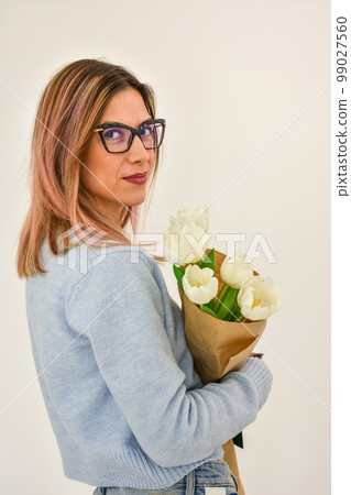 Bouquet of white tulips in a female hand on a white background. 99027560