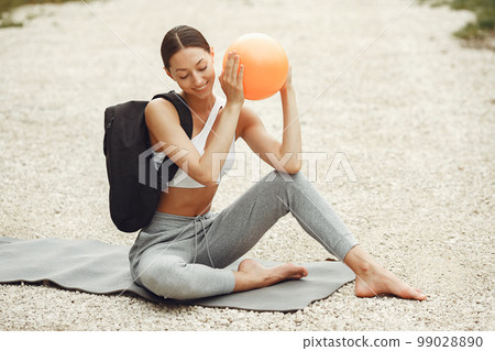 Pretty lady training on a summer beach. Brunette doing yoga. Girl in a sportsuit. Pretty lady training on a summer beach. Brunette doing yoga. Girl in a sportsuit. 99028890