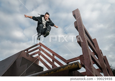Man doing parkour in city. Athlete practicing freerunning. 99029498