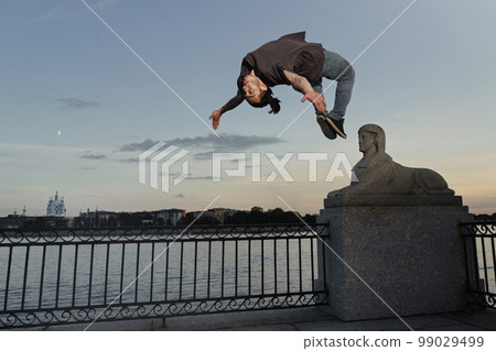 Young sporty man doing backflip in city Young sporty man doing backflip in city 99029499