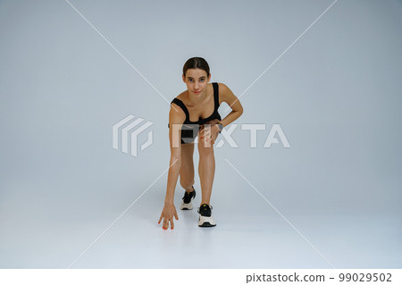 Female athlete runner before start, preparing to run on studio background. Running workout Female athlete runner before start, preparing to run on studio background. Running workout 99029502