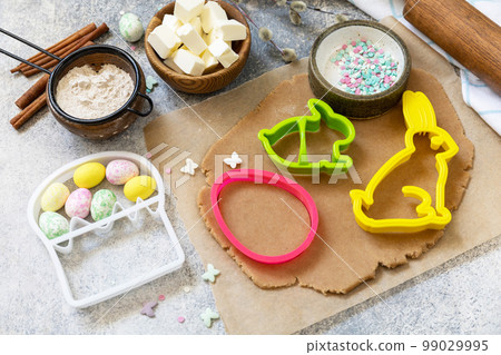 Easter baking ingredients background. Flour, eggs, milk, sugar, butter and kitchen utensils for baking on a stone table. 99029995
