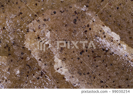 Texture of coffee and honey scrub, closeup. Cosmetic product. Smudges of honey-coffee scrub with exfoliating particles close-up. Self care and soft skin concept. Comic texture as a background. 99030254