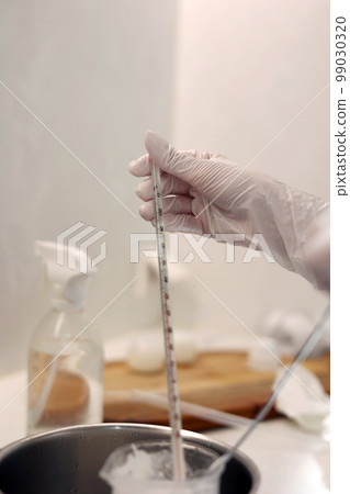 Hand holding a thermometer while boiling solution in a laboratory beaker Hand holding a thermometer while boiling solution in a laboratory beaker 99030320