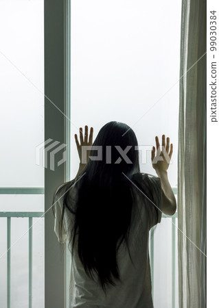 一個女人從朦朧多雲的窗戶焦急地看著外面的背影 99030384