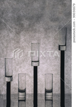 Still life with glass glasses on stands on a gray background Still life with glass glasses on stands on a gray background 99030879