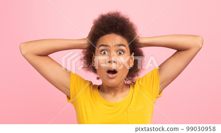 Shocked emotional young black curly woman screaming with open mouth, hold hand with hands Shocked emotional young black curly woman screaming with open mouth, hold hand with hands 99030958