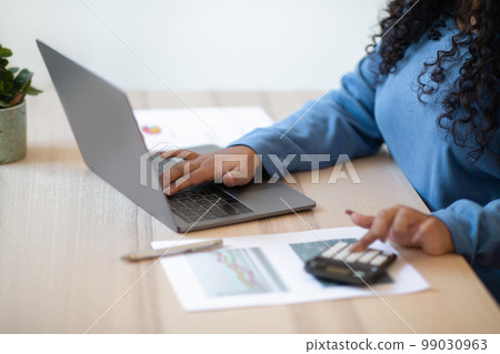 Unrecognizable woman accountant using computer and calculator 99030963