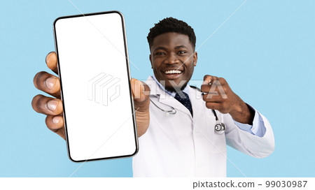 African American Male Doctor In Uniform Pointing At Smartphone With Blank Screen 99030987
