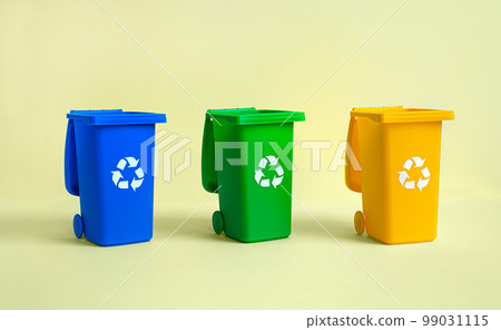 Blue, yellow and green tank for separate garbage collection on the yellow background, waste recycling and conservation of the environment concept 99031115