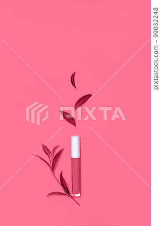 Lip gloss decorated with fresh leaf in flat lay style. Toned image in trendy magenta color of year 2023. Organic cosmetics concept. Copy space. Lip gloss decorated with fresh leaf in flat lay style. Toned image in trendy magenta color of year 2023. Organic cosmetics concept. Copy space. 99032248