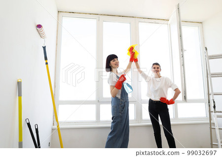 Young females washing window while working together giving high five. Young females washing window while working together giving high five. 99032697