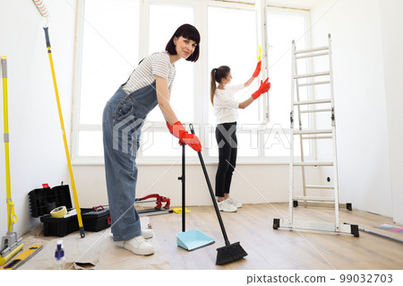 Young beautiful women cleaning up new apartment after renovation. 99032703