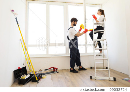 Young family of two, pretty woman sitting on ladder and bearded man household chores Young family of two, pretty woman sitting on ladder and bearded man household chores 99032724