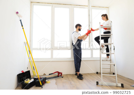 Attractive young couple in rubber gloves with detergent and rag washing windows together. Attractive young couple in rubber gloves with detergent and rag washing windows together. 99032725