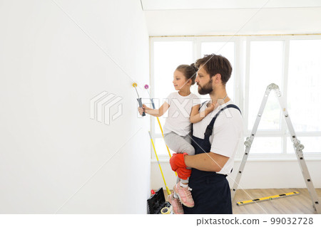 Smiling 5-year-old girl holds a paint roller in her hands. 99032728