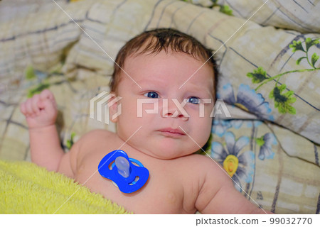 Newborn European naked baby with a pacifier on his chest 99032770