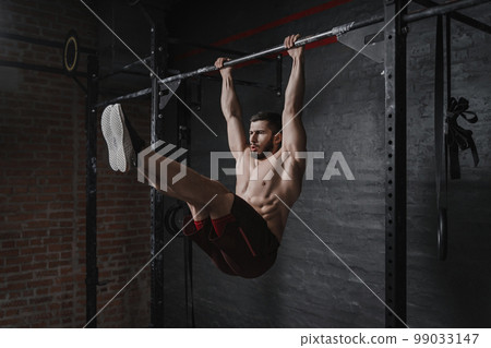 Crossfit athlete doing abs exercises on horizontal bar Crossfit athlete doing abs exercises on horizontal bar 99033147