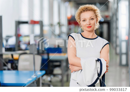 a blonde in a white dress in a big office. the concept of a business portrait.  99033817