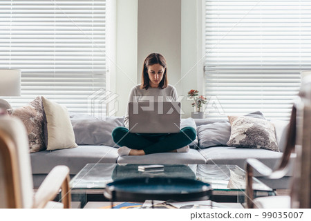 Woman using laptop computer in living room. Woman using laptop computer in living room. 99035007