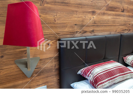 Detail of hotel bedroom with bed, pillow and red lamp on the wall Detail of hotel bedroom with bed, pillow and red lamp on the wall 99035205