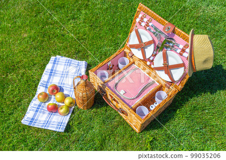 Picnic basket on green sunny lawn in the park 99035206