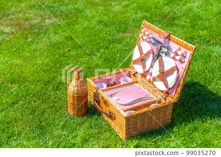 Picnic basket on green sunny lawn in the park 99035270