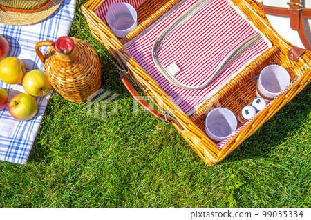 Picnic concept with basket on green sunny lawn in the park 99035334